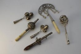 Six silver and white metal bells and children's rattles. Including two silver three bell and whistle