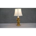 A gilded plaster cherub design table lamp with cream hexagonal shade. H.47 W.26cm