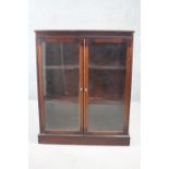 A mahogany bookcase with pair of glazed doors on plinth base. H.101 W.82 D.27 cm.