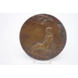 An Art Nouveau style bronze relief plaque depicting a mermaid on a rock under a tree gazing at a