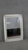 A contemporary wall mirror with beveled plate in distressed painted frame with floral decoration.