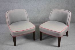 A pair of contemporary vintage style tub chairs in piped calico upholstery on tapering ebonised