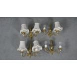 A set of four brass two branch scrolling design wall lights with cream silk shades and tassel