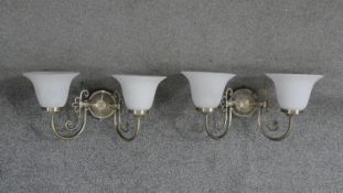 A pair of brushed brass and glass two branch wall lights. Each with two bell shaped frosted milk