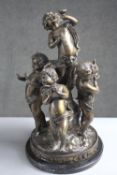 A 19th century cast spelter figure of four cherubs mounted on a black marble base. H.47 Diam. 26 cm.
