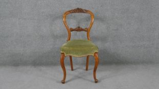 A Victorian walnut framed and ebonised dining chair with carved back rail on cabriole supports.