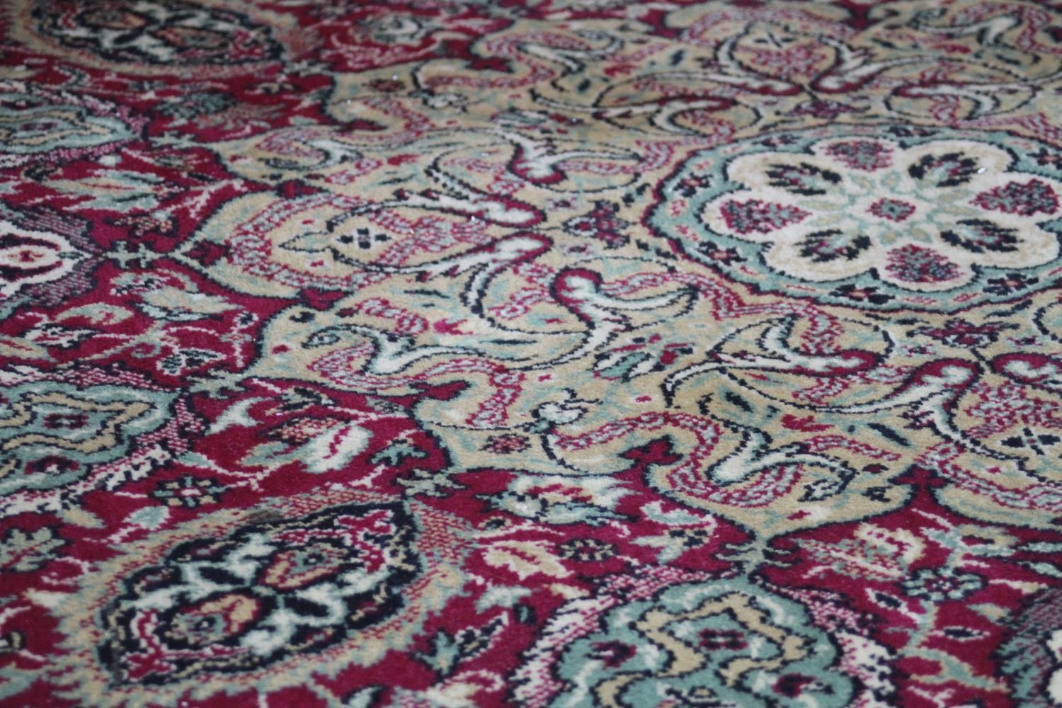 A large Wilton carpet with repeating floral medallions and trailing foliate decoration on a burgundy - Image 8 of 11