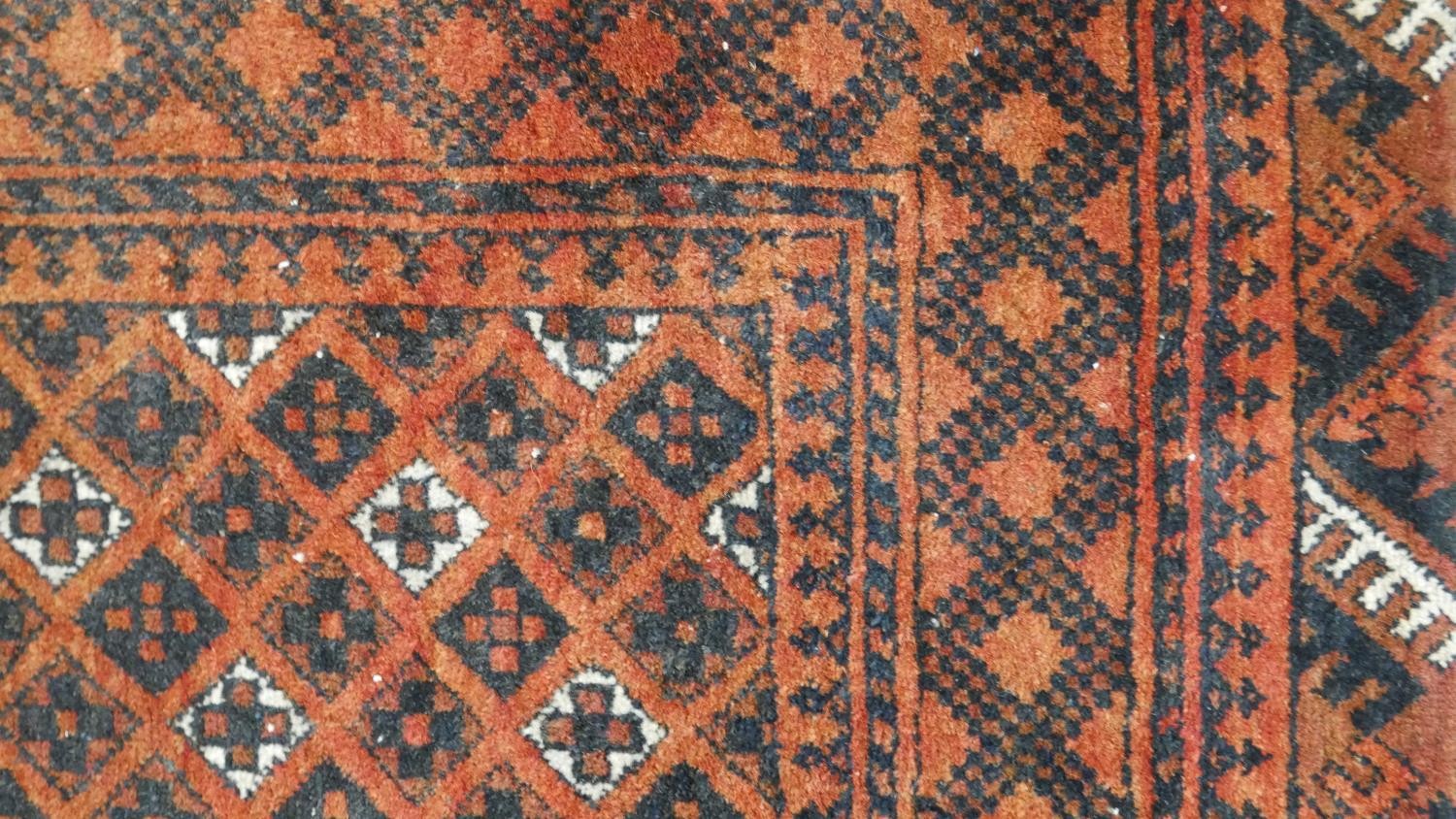 An Afghan rug with repeating stylised geometric motifs on a terracotta ground within multiple - Image 3 of 5