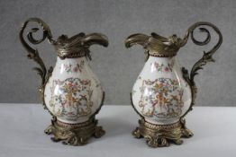 A Pair of Victorian style Wong Lee brass and ceramic jugs. The brass mounts with a scrolling foliate