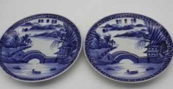 A pair of Japanese Arita style porcelain blue and white chargers hand painted with a landscape