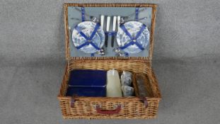 A vintage four person wicker picnic set. With blue Willow pattern crockery, dark blue tupperware and