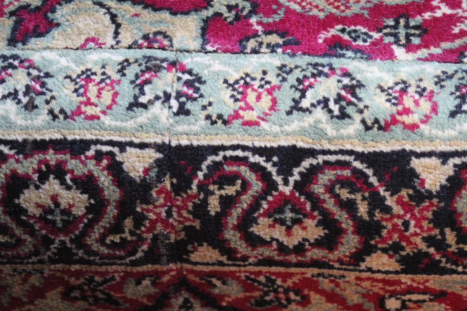 A large Wilton carpet with repeating floral medallions and trailing foliate decoration on a burgundy - Image 10 of 11