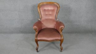 A 19th century walnut framed armchair in buttoned velour upholstery on cabriole supports.