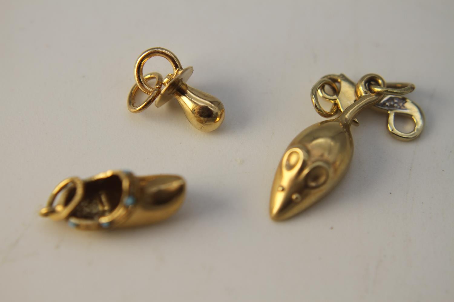 Four 14 carat yellow gold charms. Including a gold clog charm set with turquoise cabochons, a gold
