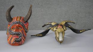 Two masks. One carved and painted with sheep's horns and the other a sheep's skull with gilt metal