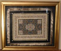 A gilt framed and glazed Persian silk rug on a black background with floral boarders. H.80 W.94cm