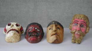 A collection of four vintage carved and painted masks including a skull and a devil. H.26 W.18 D.