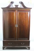 A 19th century mahogany wardrobe with pierced arched swan neck pediment above fielded panel doors