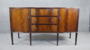 A Georgian style flame mahogany sideboard with husk carved decoration on square tapering supports.