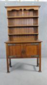 A late 19th century oak Arts and Crafts dresser with open plate rack above panel doors with embossed