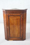 A Georgian oak hanging corner cabinet with panel door enclosing shaped shelves. H.112 W.80 D.45 cm.