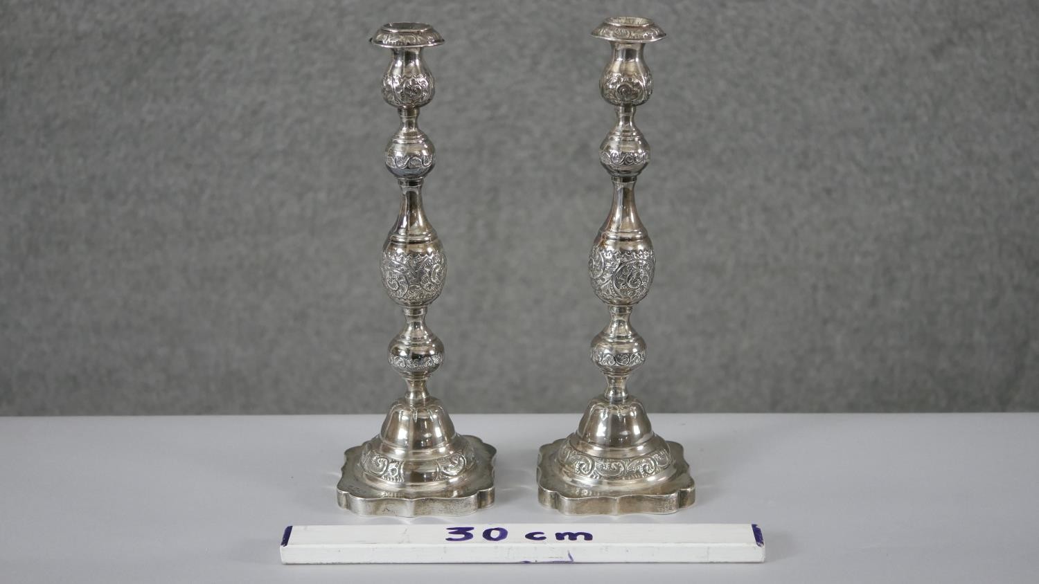 A pair of 1920'a repousse silver candlesticks with scrolling foliate design on scalloped bases. - Image 2 of 8
