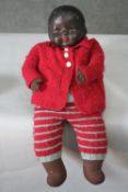 A 1930's ceramic head and cloth body African baby doll with closing eyes and woollen outfit. H.35