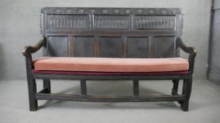 A 17th century oak hall bench with carved and panelled back above fitted pad cushion on square