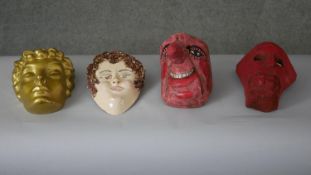 A collection of four masks. Including a gilt fibreglass mask and a ceramic mask of a young woman.
