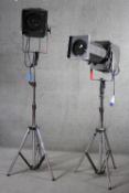 A pair of theatre follow spot lights on adjustable tripod bases. H.143 W.73cm.
