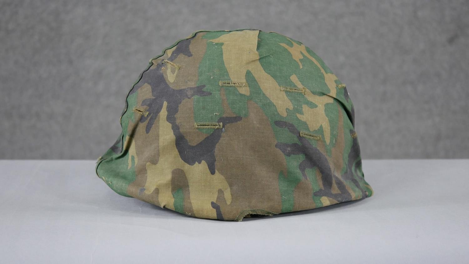 A WW2 US Schlueter helmet with camouflage canvas hood liner. H15 W.24 D.28cm