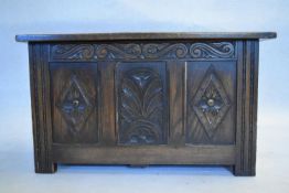 A mid century oak Jacobean style coffer with carved panels on block supports. H.47 W.84 D.45cm