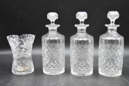 A set of three 20th century cut crystal glass topped decanters with a similar vase. H.27cm (