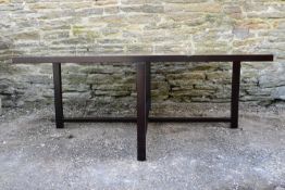 A contemporary table on ebonised X stretchered supports. H.51 W.120 D.120cm (top dented as can be