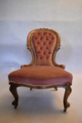 A Victorian carved walnut nursing chair in deep buttoned upholstery on cabriole supports. H.90 W.