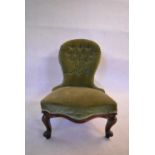 A Victorian mahogany nursing chair in deep buttoned upholstery on carved cabriole supports. H.88 W.