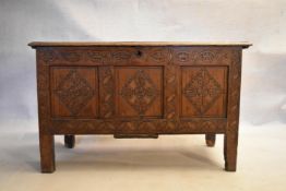 An 18th century country oak coffer with its original hinges and lozenge carved panels raised on