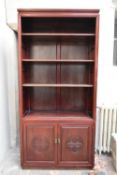 A Chinese carved teak library bookcase with open shelves above panel doors on plinth base. H.191 W.