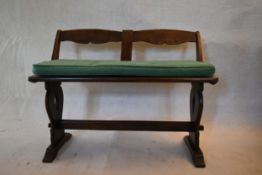 A mid century oak country antique style two seater bench on shaped stretchered supports. H.70 W.95