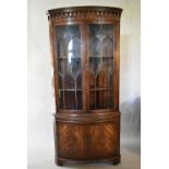 A Georgian style mahogany bow fronted corner cabinet with astragal glazed doors above candle slide