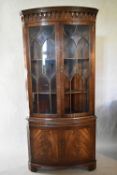 A Georgian style mahogany bow fronted corner cabinet with astragal glazed doors above candle slide