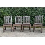 A set of four weathered teak garden chairs with carved back rails and slatted backs and seats on