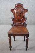 A Victorian carved mahogany hall chair with shield back above panel seat on turned tapering