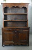 An 18th century French Provincial chestnut dresser with open plate rack above cupboards and