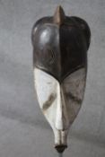 A carved and painted African DRC Gabon Fang Ngil hardwood mask. H.60 W.25cm.