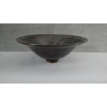 A large footed art pottery bowl with brown and black glaze with flared rim. (Damaged as seen in