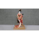 A vintage Japanese geisha girl doll on bamboo base. Dressed in a traditional silk kimono, with paper