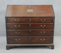 A Georgian mahogany bureau with fall front enclosing fitted interior with later embossed plaque with