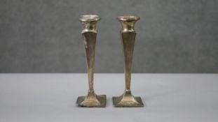 A pair of weighted hallmarked silver candlesticks of angular design. H.16 W.5 D.5cm