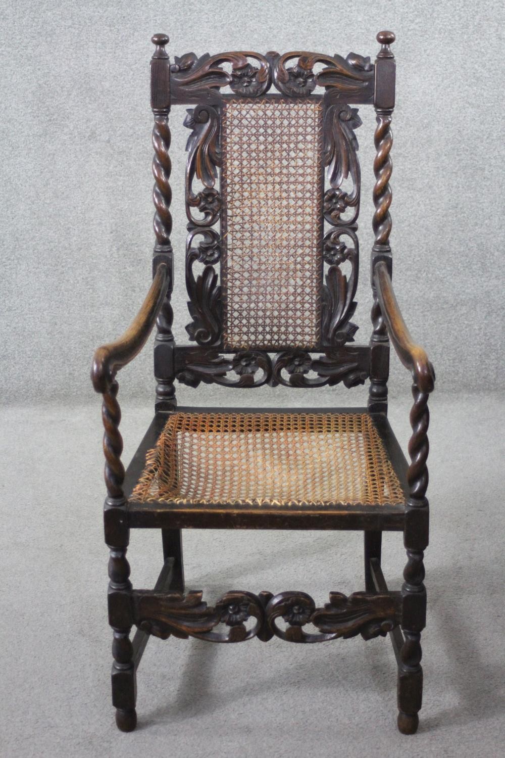 A late 19th century carved oak armchair with caned back and seat on stretchered barleytwist